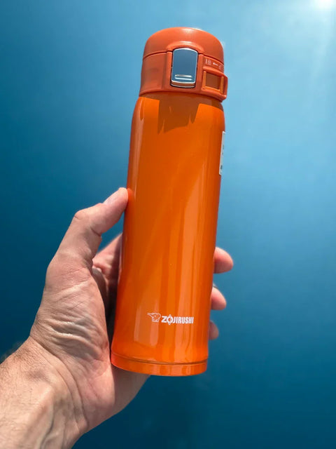 Zojirushi orange travel mug and blue sky