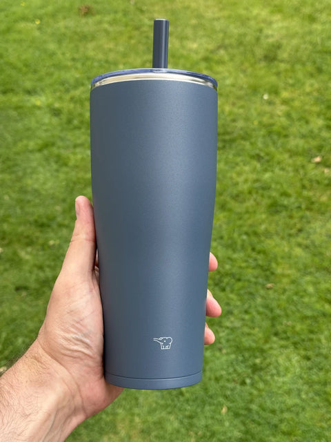 zojirushi dark blue straw tumbler in hand, background green grass